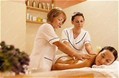 Two massage therapists working together on a client during a four-hands massage